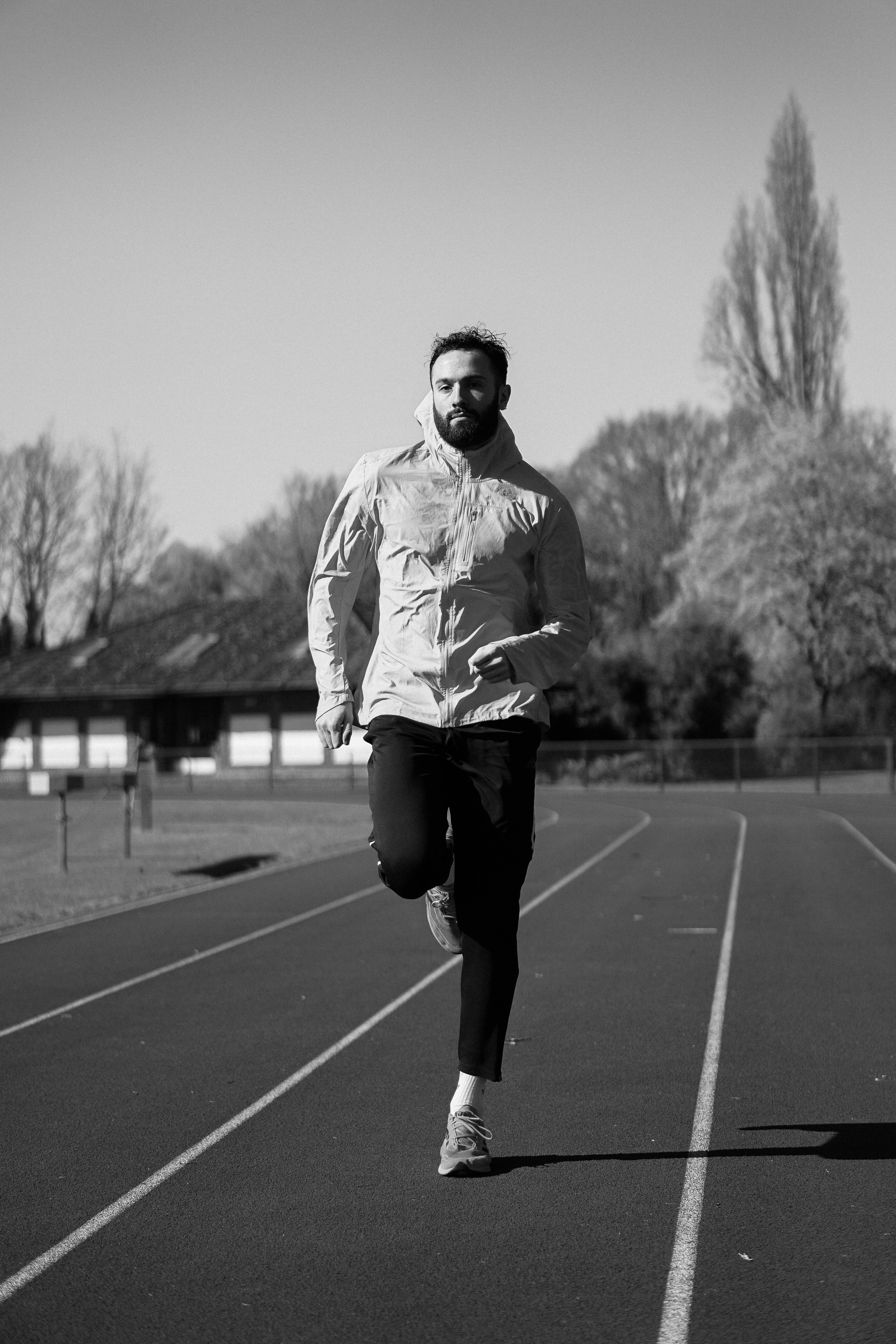 Un entrenador corriendo hacia la cámara en una pista de atletismo